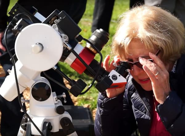 A photograph of a member of the public observing the sun through a specialist telescope.